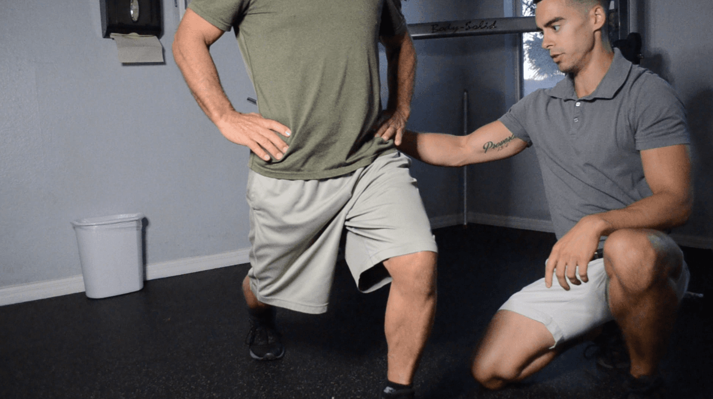 Physical therapist guiding a patient through a lunge with a hand on his hip